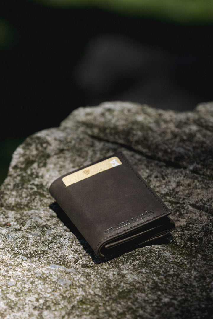 Portefeuille compact en cuir pleine fleur THASOS coloris noir, tenu en main – Ateliers Fourès