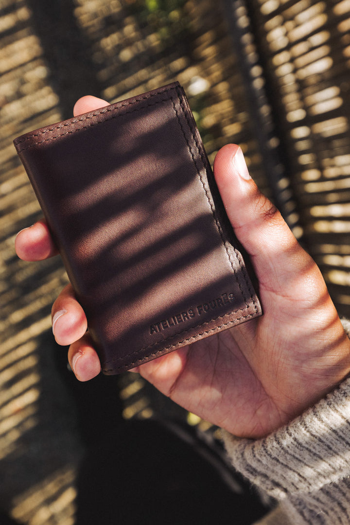 Portefeuille compact en cuir pleine fleur PLATON coloris cafe, tenu en main – Ateliers Fourès