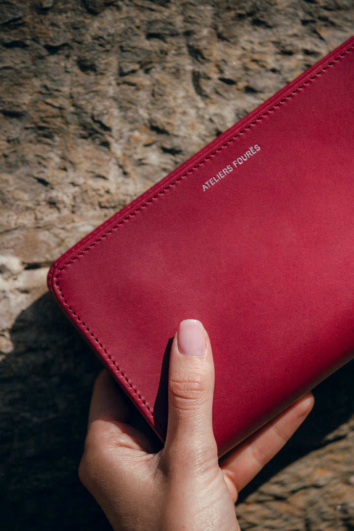 Grand portefeuille en cuir pleine fleur PERSÉPHONE coloris pourpre, tenu en main n°1 – Ateliers Fourès