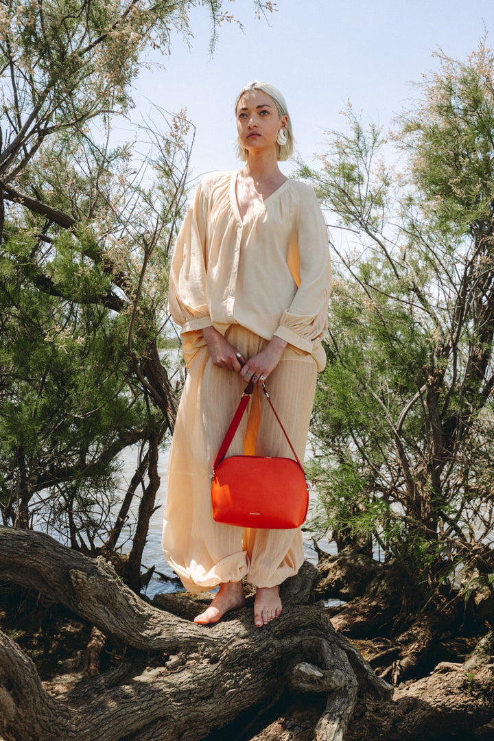 Sac bandoulière en cuir pleine fleur ODYSSÉE coloris orange, porté n°1 – Ateliers Fourès