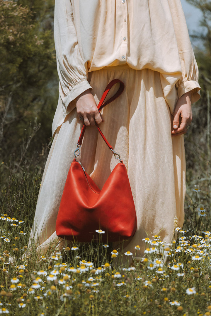 Sac bandoulière en cuir pleine fleur ILIADE coloris orange confit, porté à l’épaule n°1 – Ateliers Fourès